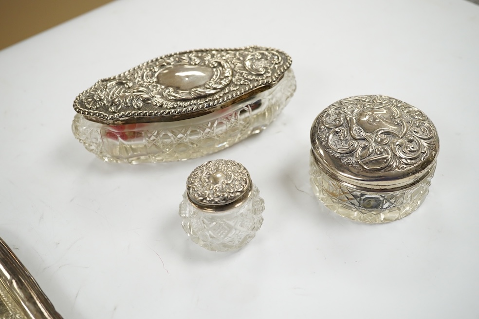 A George V repousse silver dressing table tray, William Neale Ltd, Birmingham, 1910, 29.1cm, two silver cigarette cases, a George III silver christening mug (a.f.) and four silver mounted glass toilet jars. Condition - p